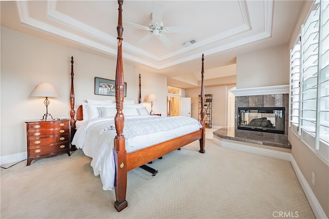 carpeted bedroom featuring a tray ceiling, multiple windows, and visible vents