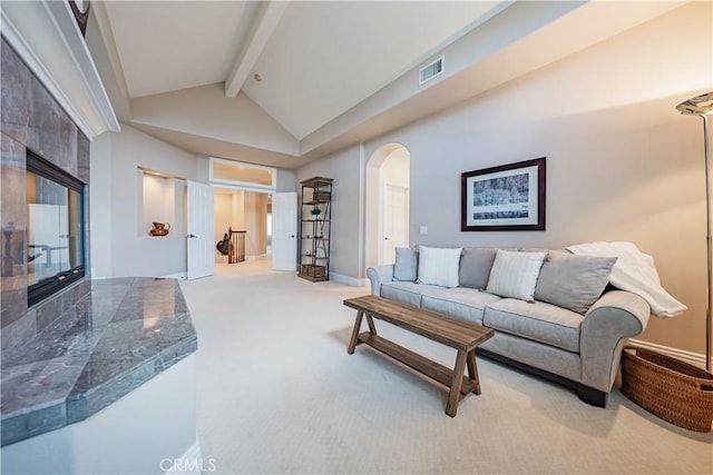 living room with visible vents, carpet floors, beam ceiling, arched walkways, and high vaulted ceiling