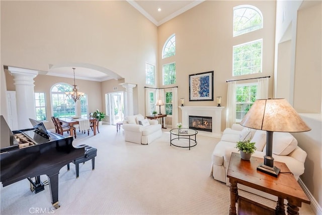 sitting room with ornamental molding, a glass covered fireplace, arched walkways, carpet flooring, and ornate columns