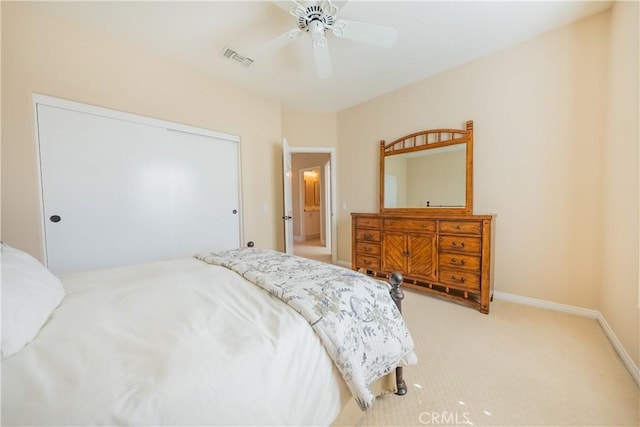 bedroom with visible vents, baseboards, ceiling fan, light colored carpet, and a closet