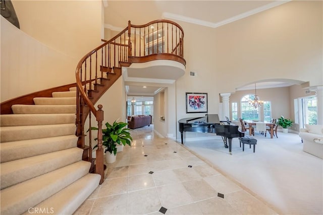 foyer featuring stairway, an inviting chandelier, a high ceiling, arched walkways, and ornamental molding