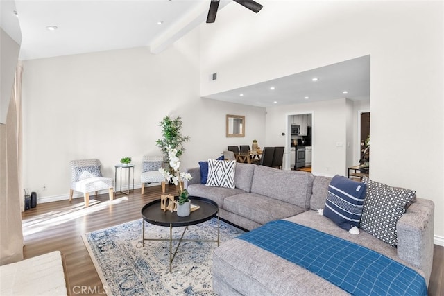 living area with high vaulted ceiling, wood finished floors, visible vents, baseboards, and beam ceiling