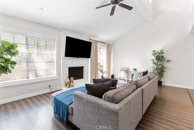 living room featuring vaulted ceiling with beams, a fireplace, ceiling fan, wood finished floors, and baseboards