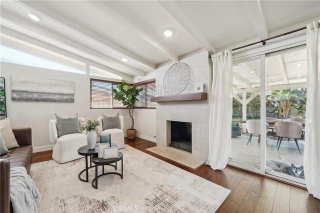 living room with baseboards, lofted ceiling with beams, wood-type flooring, a fireplace, and recessed lighting