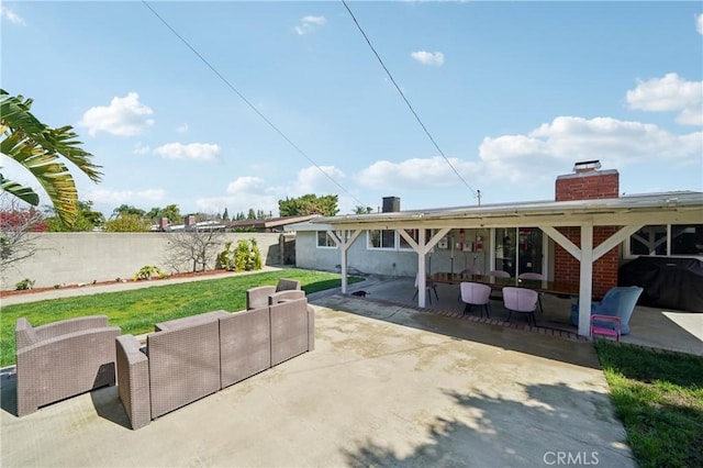 rear view of property featuring outdoor lounge area, a patio, a lawn, and fence