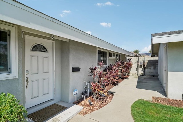 property entrance featuring a gate and stucco siding