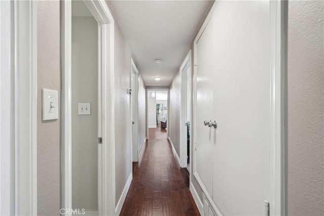 corridor with dark wood finished floors and baseboards