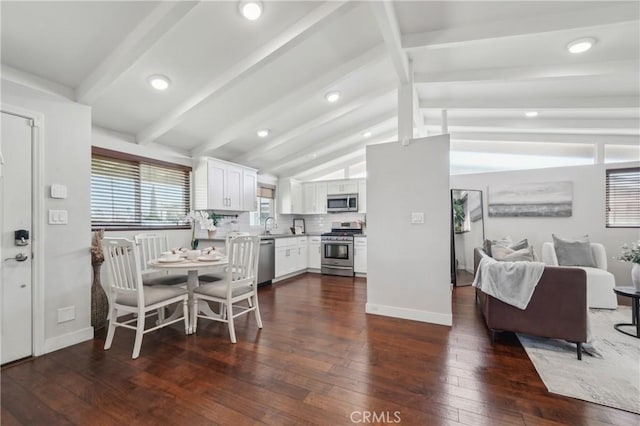 kitchen featuring lofted ceiling with beams, stainless steel appliances, dark wood-type flooring, white cabinetry, and open floor plan