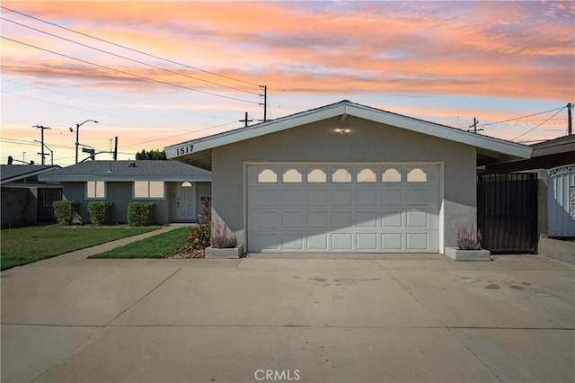 ranch-style home featuring an attached garage, fence, concrete driveway, and stucco siding