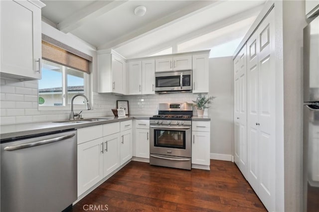 kitchen with lofted ceiling with beams, stainless steel appliances, dark wood-style flooring, a sink, and tasteful backsplash