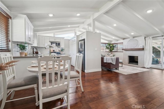 dining space with baseboards, a high end fireplace, lofted ceiling with beams, dark wood-style floors, and recessed lighting