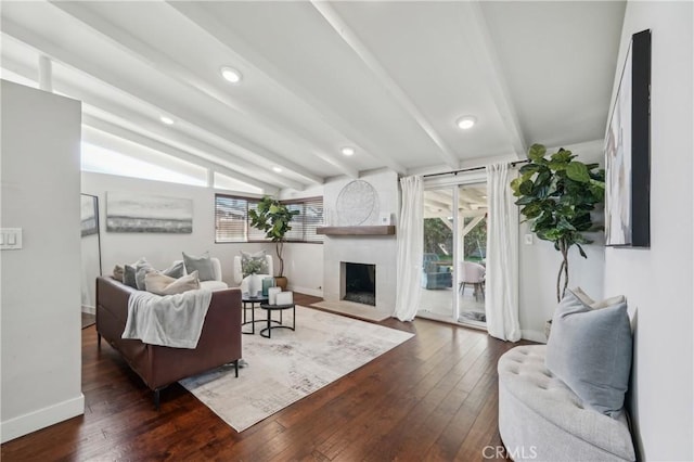 living area with baseboards, dark wood finished floors, lofted ceiling with beams, a fireplace with flush hearth, and recessed lighting