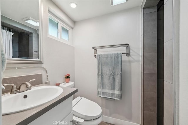 bathroom with tiled shower, vanity, and toilet