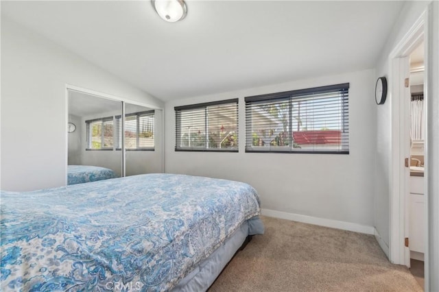 carpeted bedroom featuring lofted ceiling, baseboards, and a closet