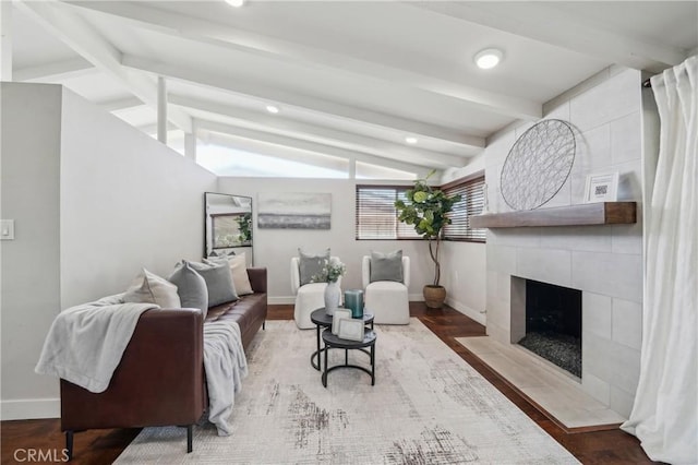 living area with lofted ceiling with beams, a fireplace, baseboards, and wood finished floors