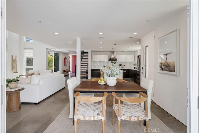 dining space with finished concrete flooring, stairway, and recessed lighting