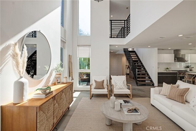 living room with recessed lighting, a towering ceiling, and stairs