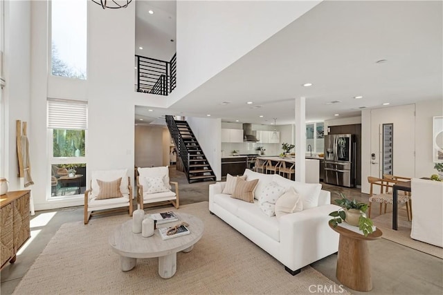 living area with stairs, a towering ceiling, and recessed lighting