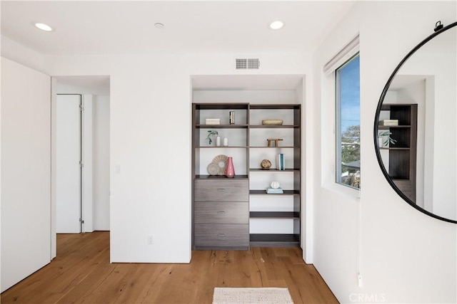 hall featuring light wood-type flooring, visible vents, and recessed lighting