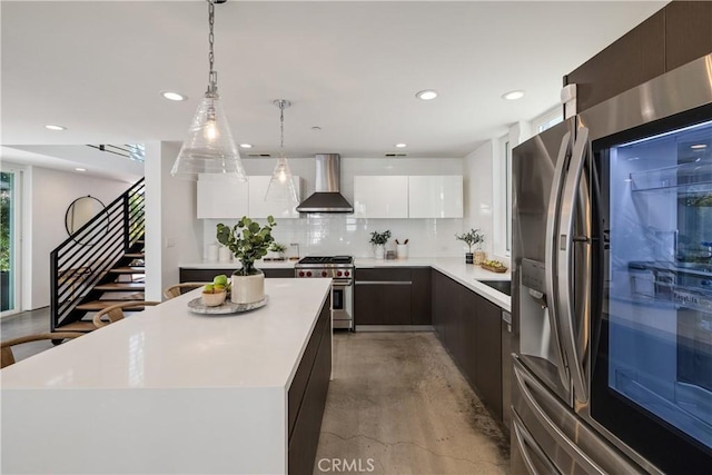 kitchen featuring wall chimney exhaust hood, modern cabinets, stainless steel appliances, light countertops, and white cabinetry