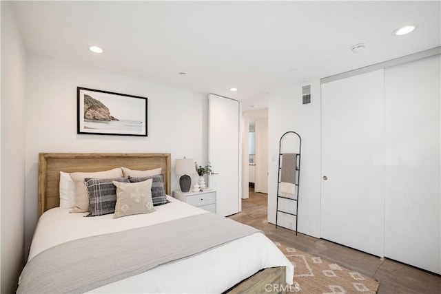 bedroom with light wood-style floors, visible vents, a closet, and recessed lighting