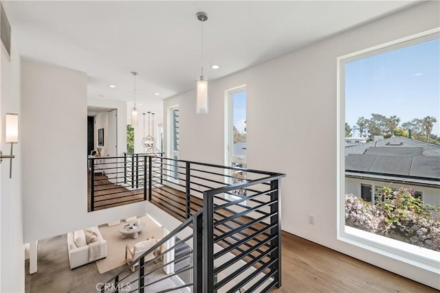 hall with wood finished floors, an upstairs landing, and recessed lighting