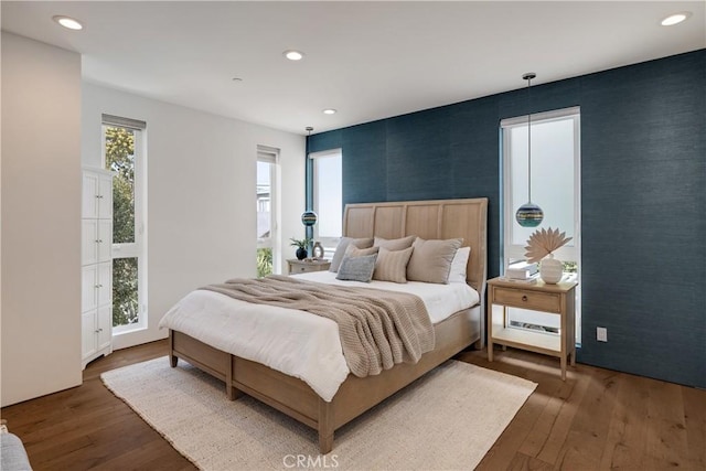 bedroom featuring an accent wall, hardwood / wood-style floors, and wallpapered walls