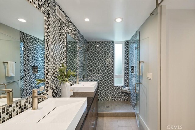 full bathroom featuring tile walls, backsplash, a shower stall, vanity, and tile patterned flooring