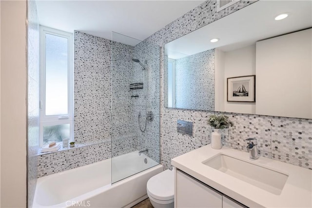 full bath featuring toilet, plenty of natural light, bath / shower combo with glass door, and vanity