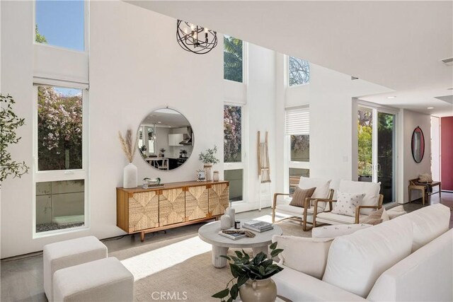 living room with visible vents, a notable chandelier, a towering ceiling, and recessed lighting