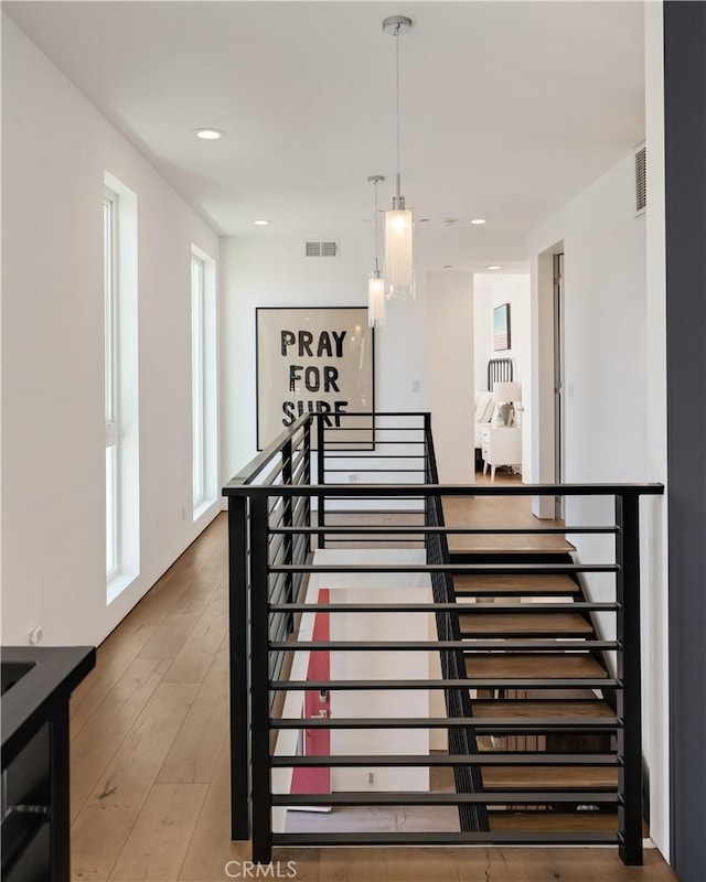 stairway with visible vents, hardwood / wood-style floors, and recessed lighting