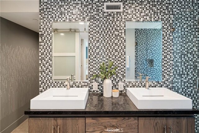 full bathroom featuring visible vents, a sink, decorative backsplash, and double vanity