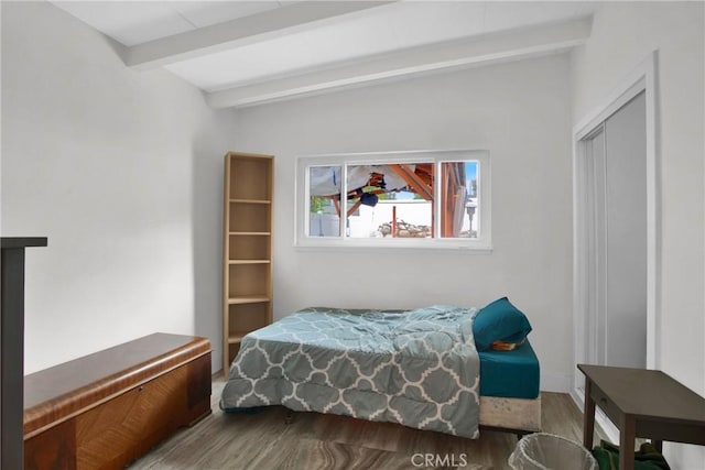 bedroom featuring a closet, beam ceiling, and wood finished floors