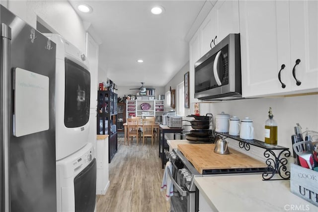 kitchen featuring stacked washer / dryer, appliances with stainless steel finishes, light wood-style floors, white cabinetry, and recessed lighting