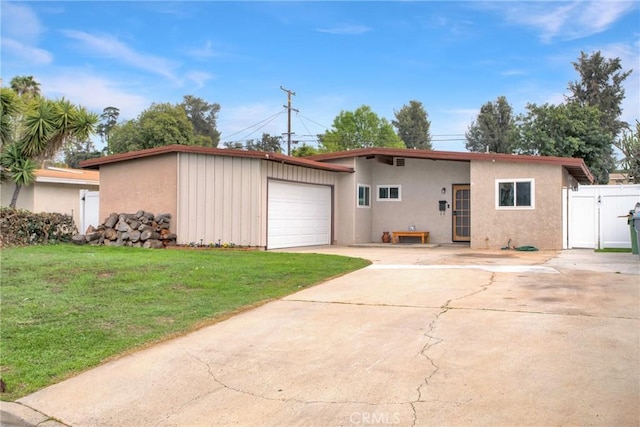 view of front of home featuring stucco siding, a gate, concrete driveway, and a front yard