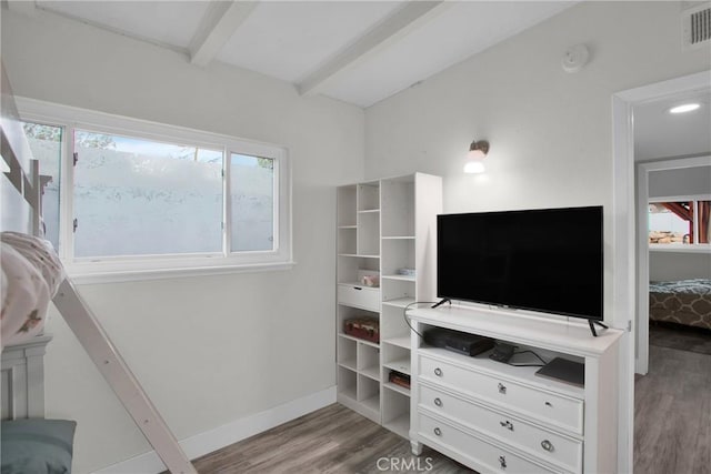 bedroom featuring visible vents, baseboards, beamed ceiling, and wood finished floors