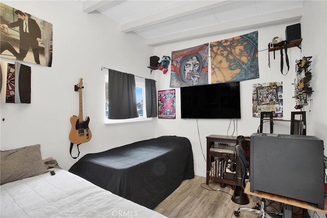 bedroom featuring beamed ceiling and wood finished floors