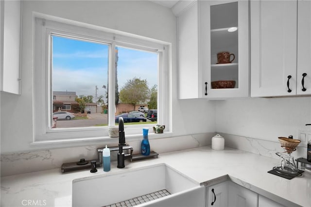 interior space featuring glass insert cabinets, a sink, and white cabinetry