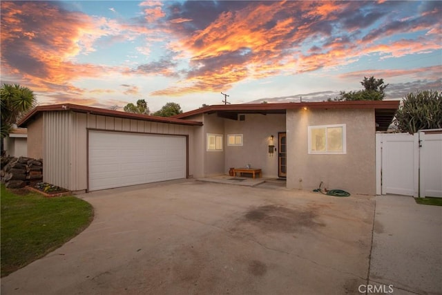 view of front of property featuring driveway, a gate, fence, and stucco siding