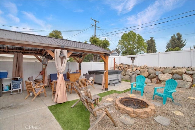 view of patio / terrace featuring a gazebo, an outdoor fire pit, a fenced backyard, and a hot tub