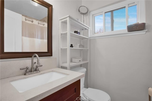 bathroom with toilet, a shower with shower curtain, and vanity