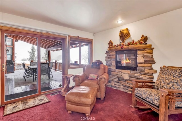 living room featuring a stone fireplace, carpet, and visible vents