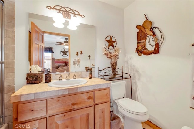 ensuite bathroom with ceiling fan, vanity, toilet, and ensuite bathroom