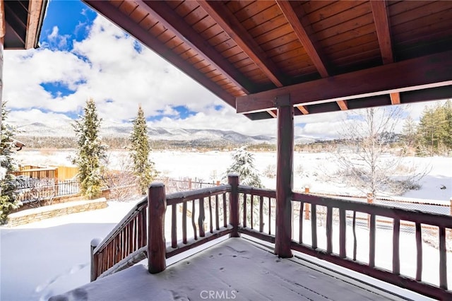 snow covered deck featuring fence and a mountain view