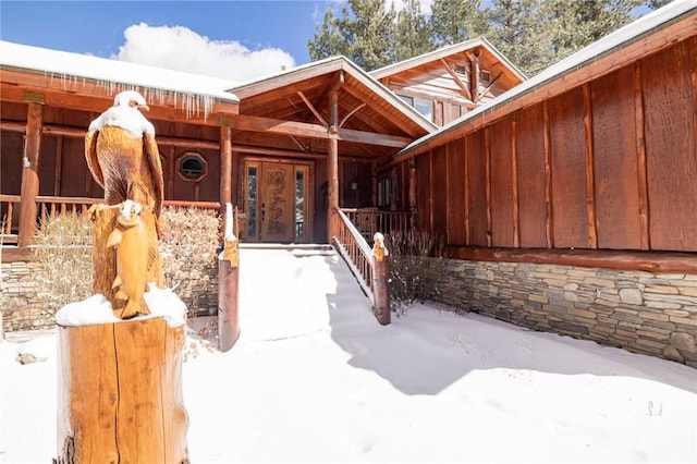 snow covered property entrance with board and batten siding