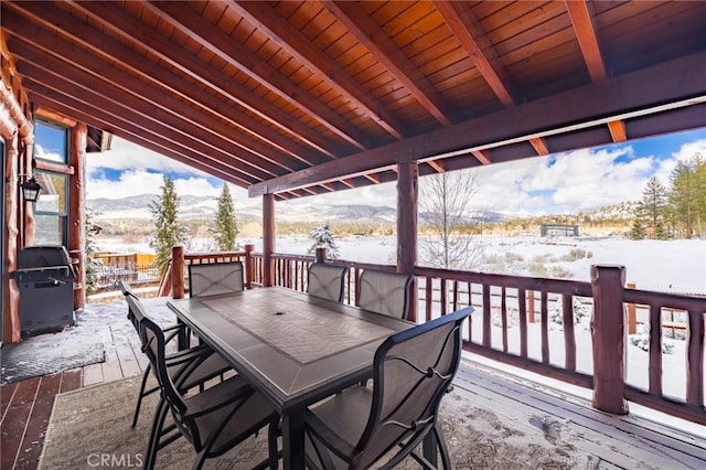 snow covered deck featuring outdoor dining space, a grill, and a mountain view