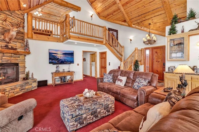 carpeted living area with beam ceiling, a fireplace, an inviting chandelier, wooden ceiling, and stairs