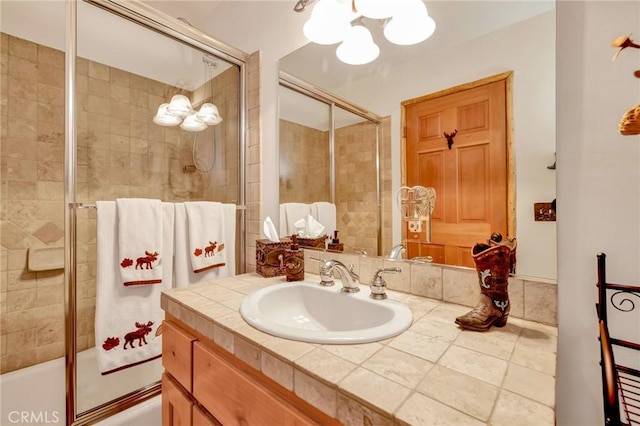 bathroom featuring bath / shower combo with glass door, vanity, and an inviting chandelier