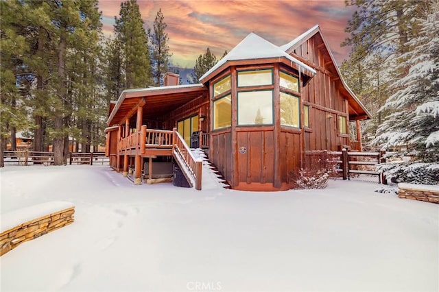 view of snow covered exterior featuring stairway, fence, and board and batten siding