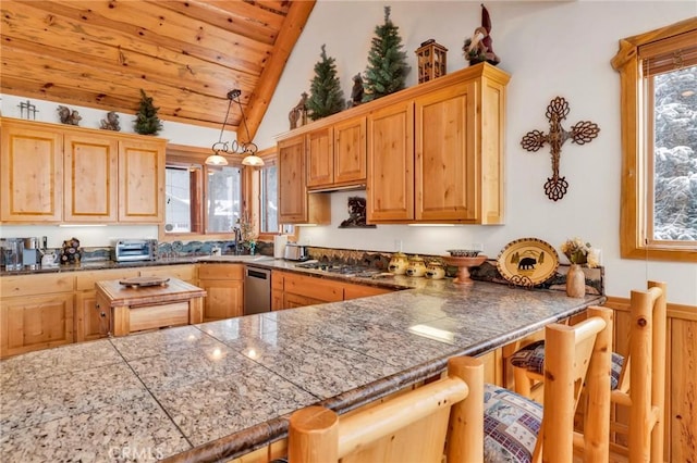 kitchen featuring tile counters, lofted ceiling, appliances with stainless steel finishes, a sink, and a kitchen bar